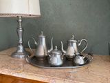 un plateau avec des théières en argent et une lampe posés sur une table