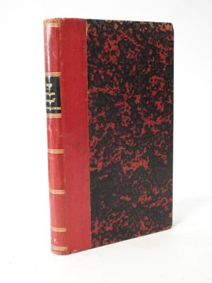 an old red and black book sitting on top of a white surface