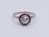 a close up of a diamond and ruby ring on a white surface