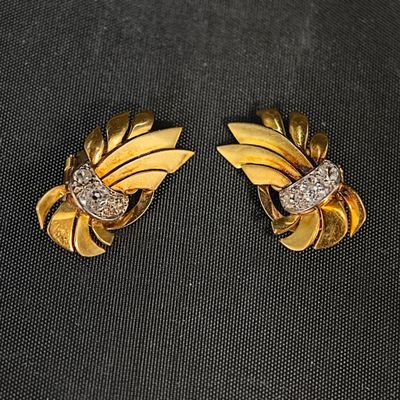 une paire de boucles d'oreilles en or et diamants sur une surface noire