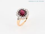 gros plan d'une bague avec une pierre rouge entourée de diamants