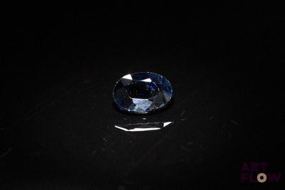 a close up of a blue diamond on a black surface