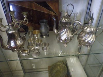 a glass display case with many silver items on it