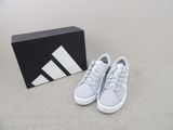 Les baskets adidas sont blanches et argentées, avec une boîte noire.