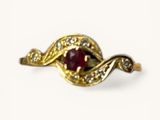 une image représentant une bague en or sertie d'une pierre rouge entourée de diamants