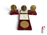 three gold medals are on display in a red display case