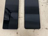 two black samsung phones sitting side by side on a table