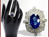 un gros plan sur la main d'une personne portant une bague, sur laquelle est sertie une pierre bleue