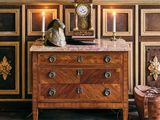 une commode sur laquelle est posée une horloge, dans une pièce