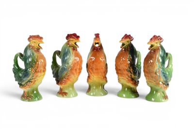 quatre figurines en céramique représentant des coqs sont alignées sur une surface blanche