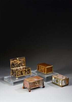 three small boxes and a small chest on display on a table