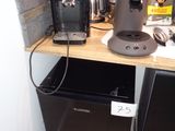 une cafetière posée sur une étagère à côté d'un réfrigérateur