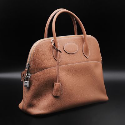 a brown leather handbag on a black background