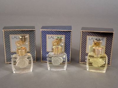 trois flacons de parfum posés les uns à côté des autres sur une table
