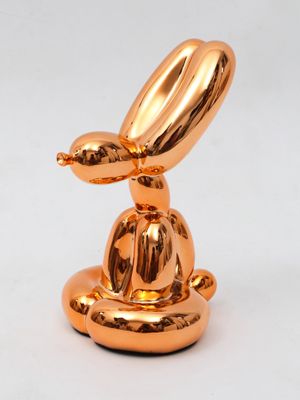 an image of a gold sculpture of a rabbit sitting on top of a plate