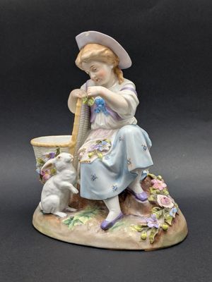 une figurine représentant une fillette avec un chien et un arrosoir