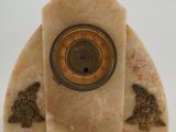 marble clock with a clock face on top of it on a white surface