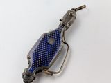 une image représentant une broche en forme de bouteille bleue posée sur une surface blanche