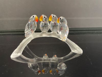 une figurine en verre représentant un groupe d'oiseaux perchés sur une branche