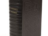 a black book with gold lettering sitting on top of a white surface