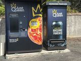 two vending machines in the parking lot of a pizza place