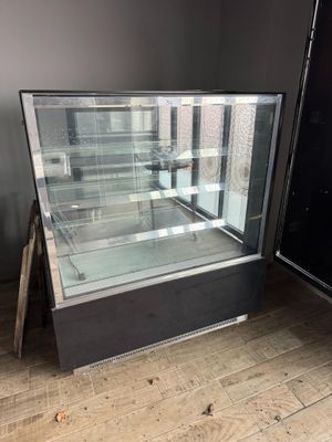 an empty glass display case in the corner of a room
