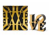 two gold and black love sculptures next to each other on a white surface
