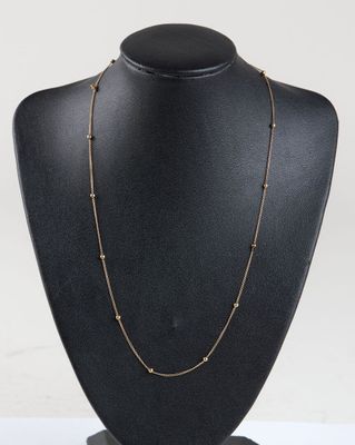 a black mannequin necklace with gold beads on a black mannequin