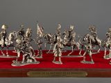 seven figurines of men riding horses on a red cloth