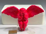 a red angel figurine sitting on a clear base