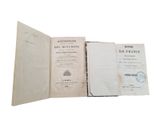 an open book sitting on top of a white table next to a clock