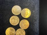a close up of a bunch of gold coins sitting on top of a black surface