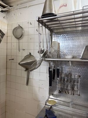 une cuisine équipée d'un évier, d'une cuisinière et de casseroles et poêles accrochées au mur