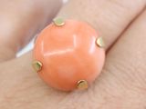 someone is holding a ring in their hand with an orange stone on it