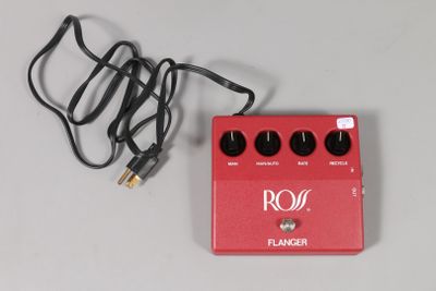 a red guitar pedal sitting on a table next to a cord