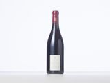 a bottle of red wine sitting on top of a white table