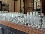 bottles and glasses lined up on a bar with a mirror in the background