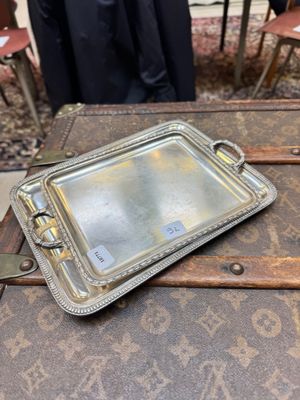 un plateau en argent posé sur une vieille valise