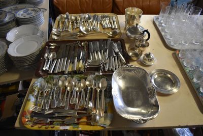 a lot of silverware on a table with a couch in the background