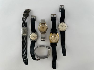 trois montres et un bracelet de montre sont posés sur une surface blanche