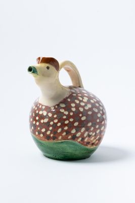 un petit vase avec un oiseau sur une surface blanche