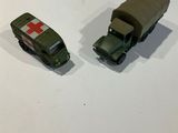 two toy army vehicles sitting on a white surface