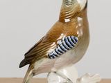 a figurine of a bird sitting on a tree branch