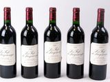 quatre bouteilles de vin rouge sont alignées sur une surface blanche