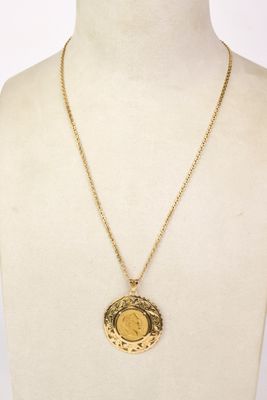 a gold necklace with a coin on a mannequin neck
