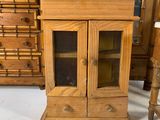 a small wooden cabinet with a glass door next to a dresser