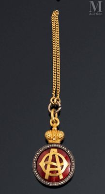 a close up of a gold and red pendant with a crown on it