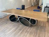 une table en bois sur laquelle sont posés des tuyaux métalliques, au milieu d'une pièce