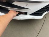a close up of a person ' s hand touching the front bumper of a car