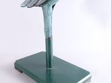 statue of a bird on a green base on a white background